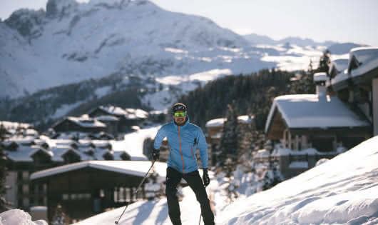 Un fondeur pratique le ski de fond sur une piste damée de la station de Courchevel