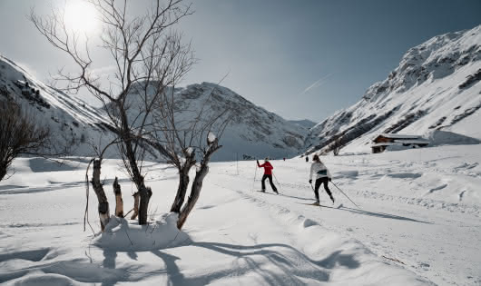 Ski de fond dans la magnifique vallée du Manchet à Val d'Isère avec deux personnes en arrière plan