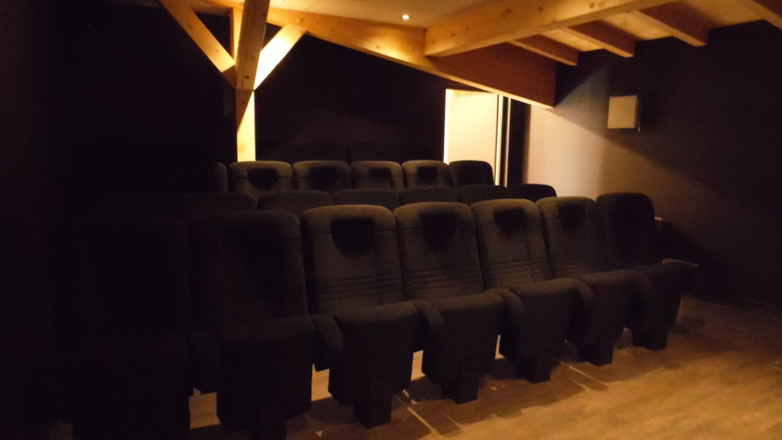 Sièges d'une petite salle de cinéma sous une charpente de bois