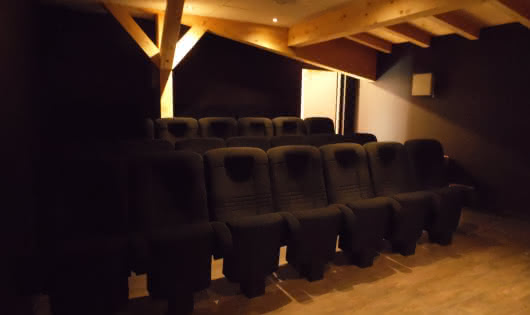 Sièges d'une petite salle de cinéma sous une charpente de bois