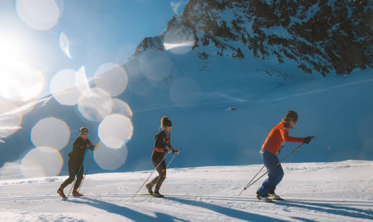 3 skieurs pratiquent le ski de fond sur une piste de skating
