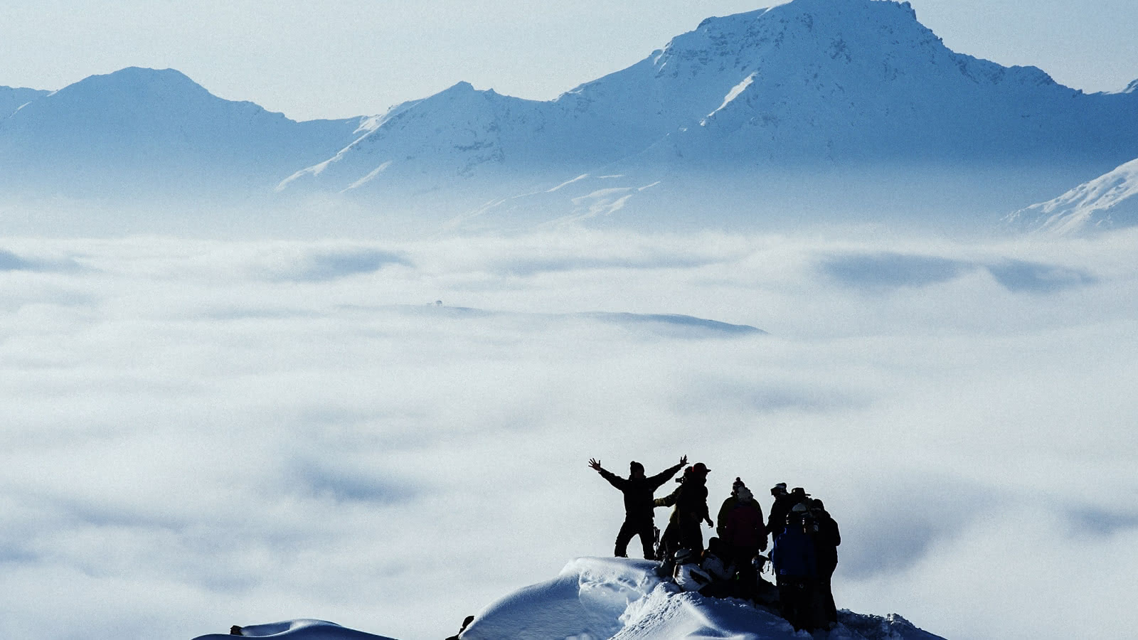 Un groupe de randonneurs est au sommet au dessus d'une mer de nuage dans les 3 vallées