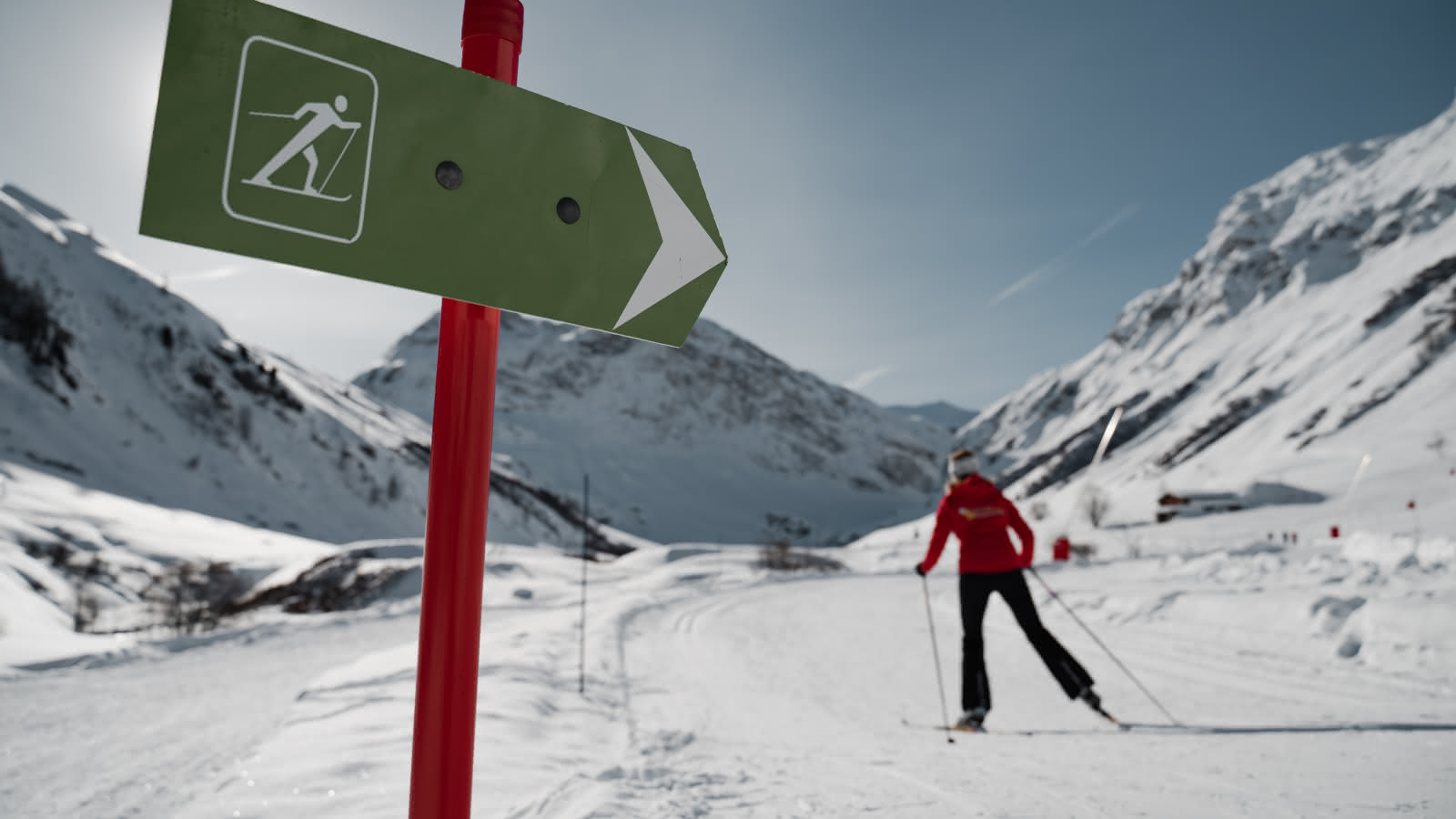 Ski de fond dans la magnifique vallée du Manchet à Val d'Isère avec un personne en arrière plan et le panneau des pistes en premier plan