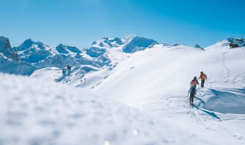 3 skieurs pratiquent le ski de randonnée en journée dans sur une piste des 3 vallées