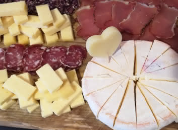 Un plateau de dégustation avec du saucisson, du Beaufory et un reblochon surmonté d'un morceau de fromage en forme de coeur